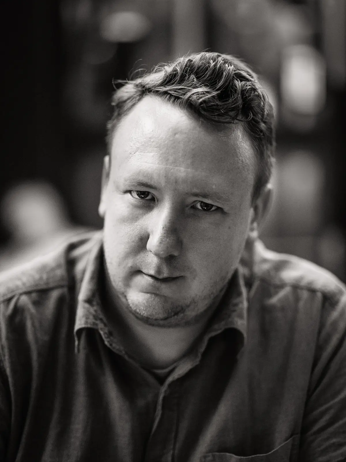 Black and white image of Photographer Andreas Feydt. Mid-torso, head leaning forward with a strong gaze straight into the camera.