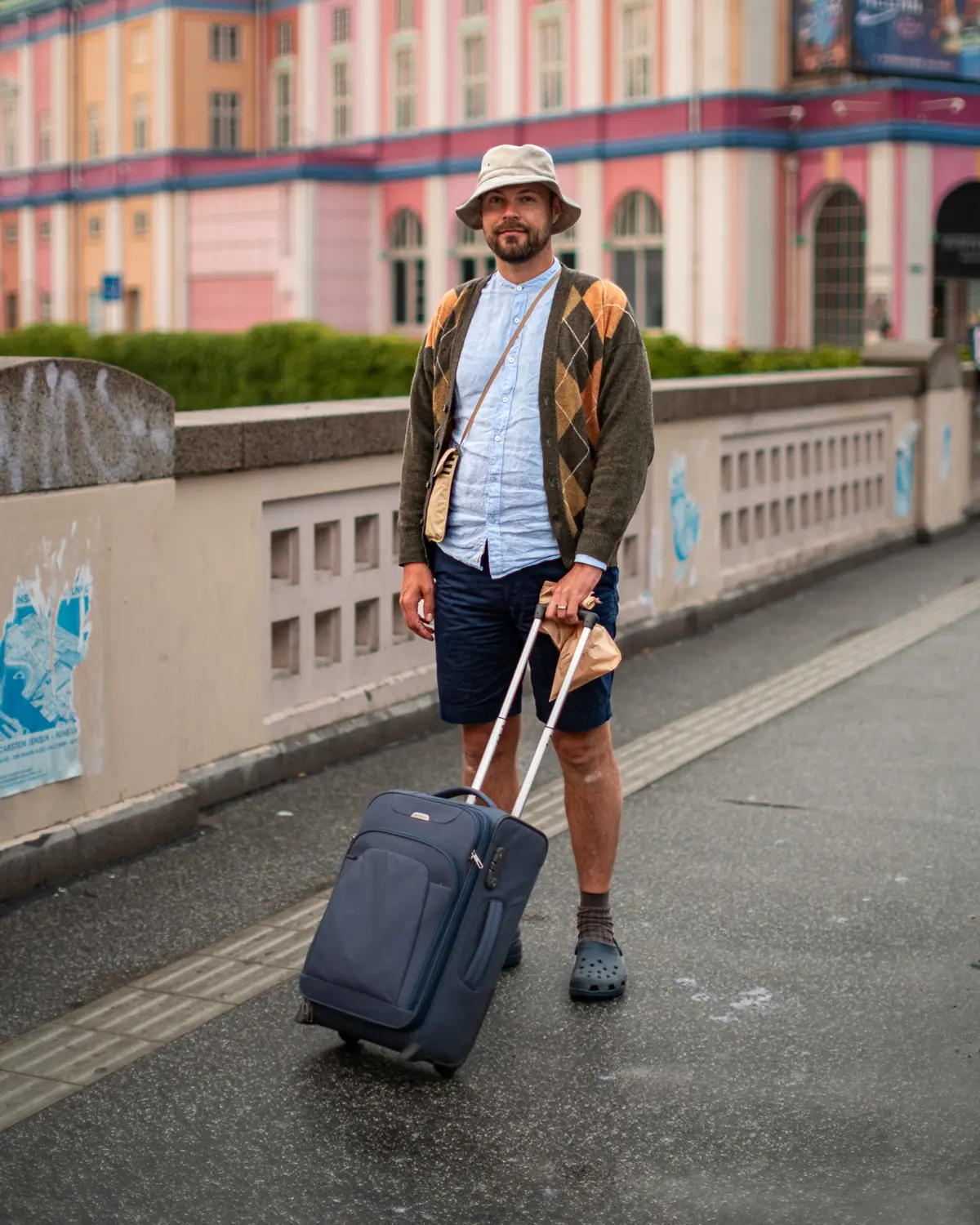 Man moving his belongings in a roller case wearing temporary attire.