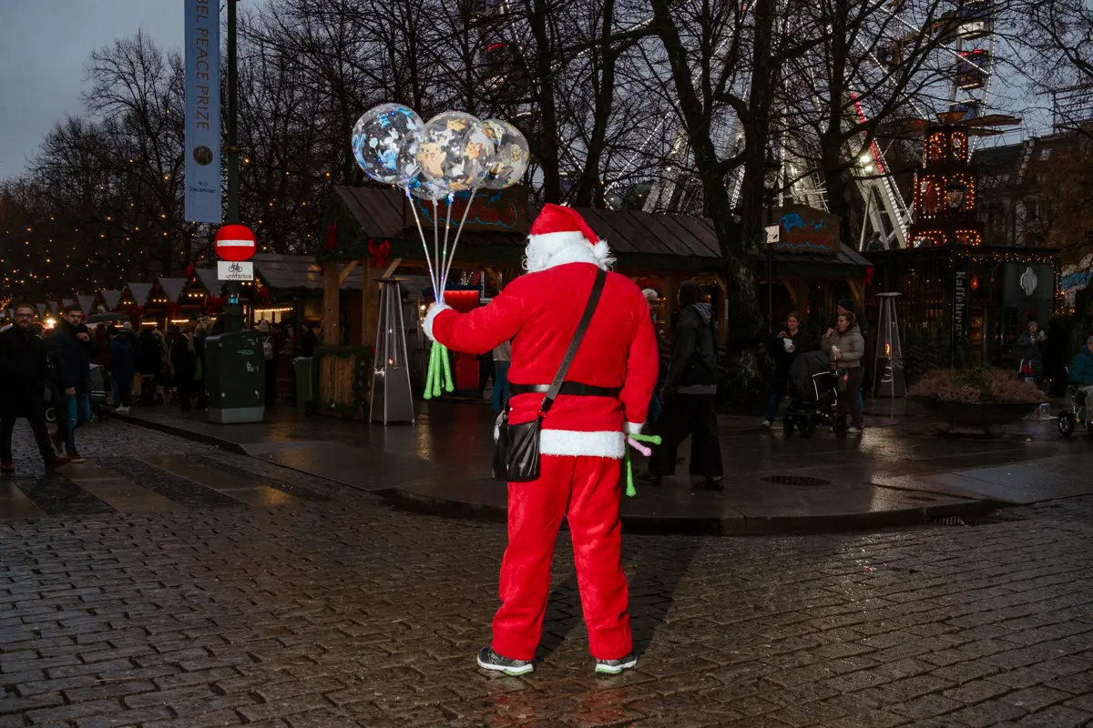 LED-filled balloon salesman in cheap santa costume on the wet Norvemner streets of Oslo.