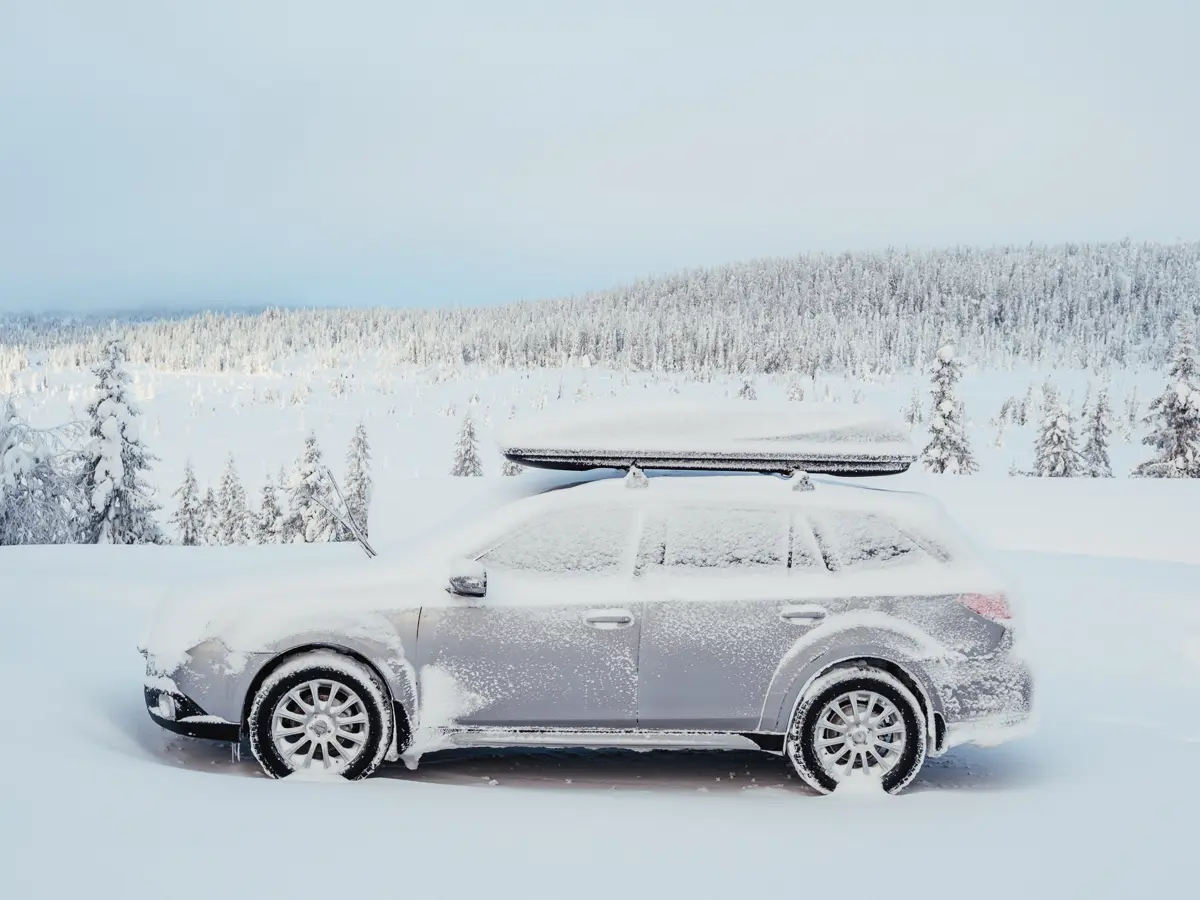 Station wagon with roof mounted ski box. Light show coating in a very white landscape.