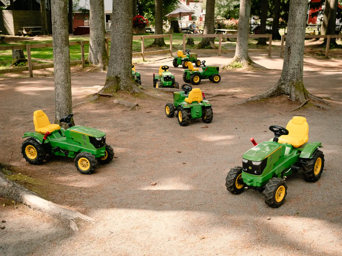 Yellow and green toy pedal tractors in the woods.