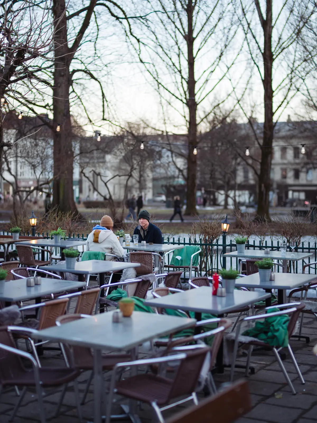 Couple in an otherwise empty outdoor restaurant trying to have a beer outside without freezing too much.