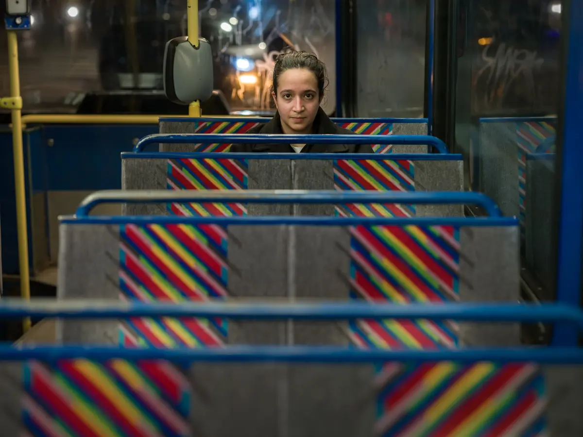 Young woman seated on the back seat row with three seat rows stacked in front of her.