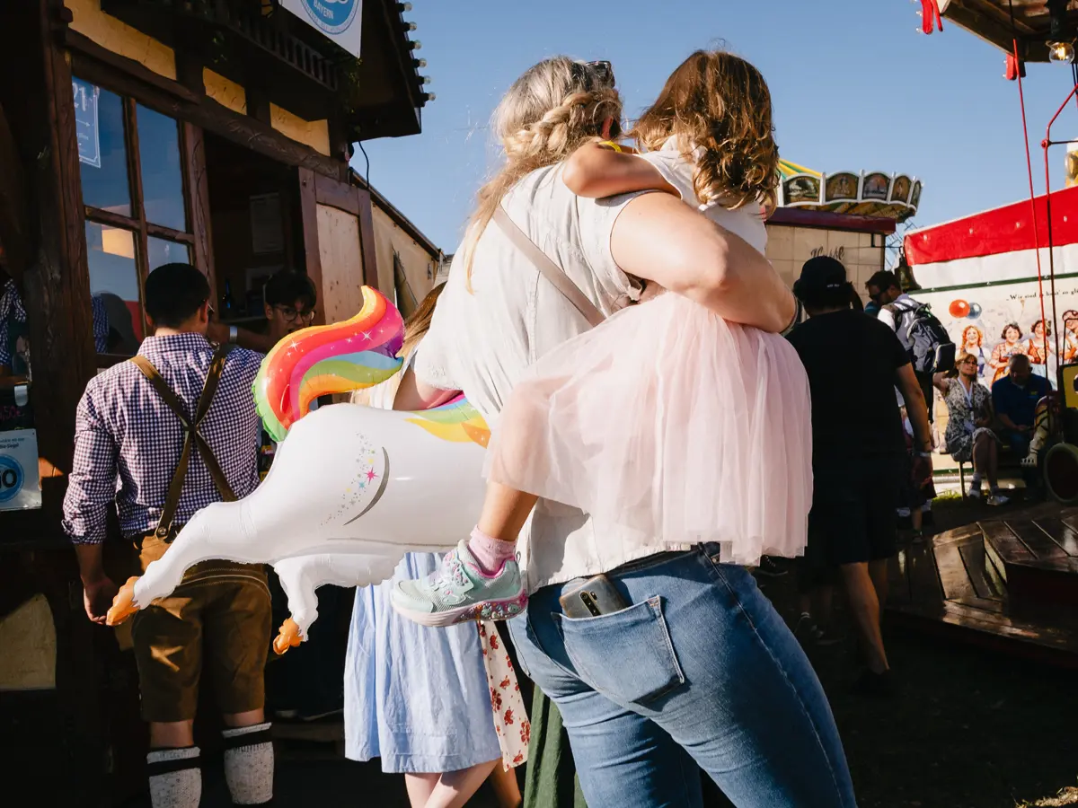 Woman carrying her daughter on the right arm and an inflated unicorn under her left.
