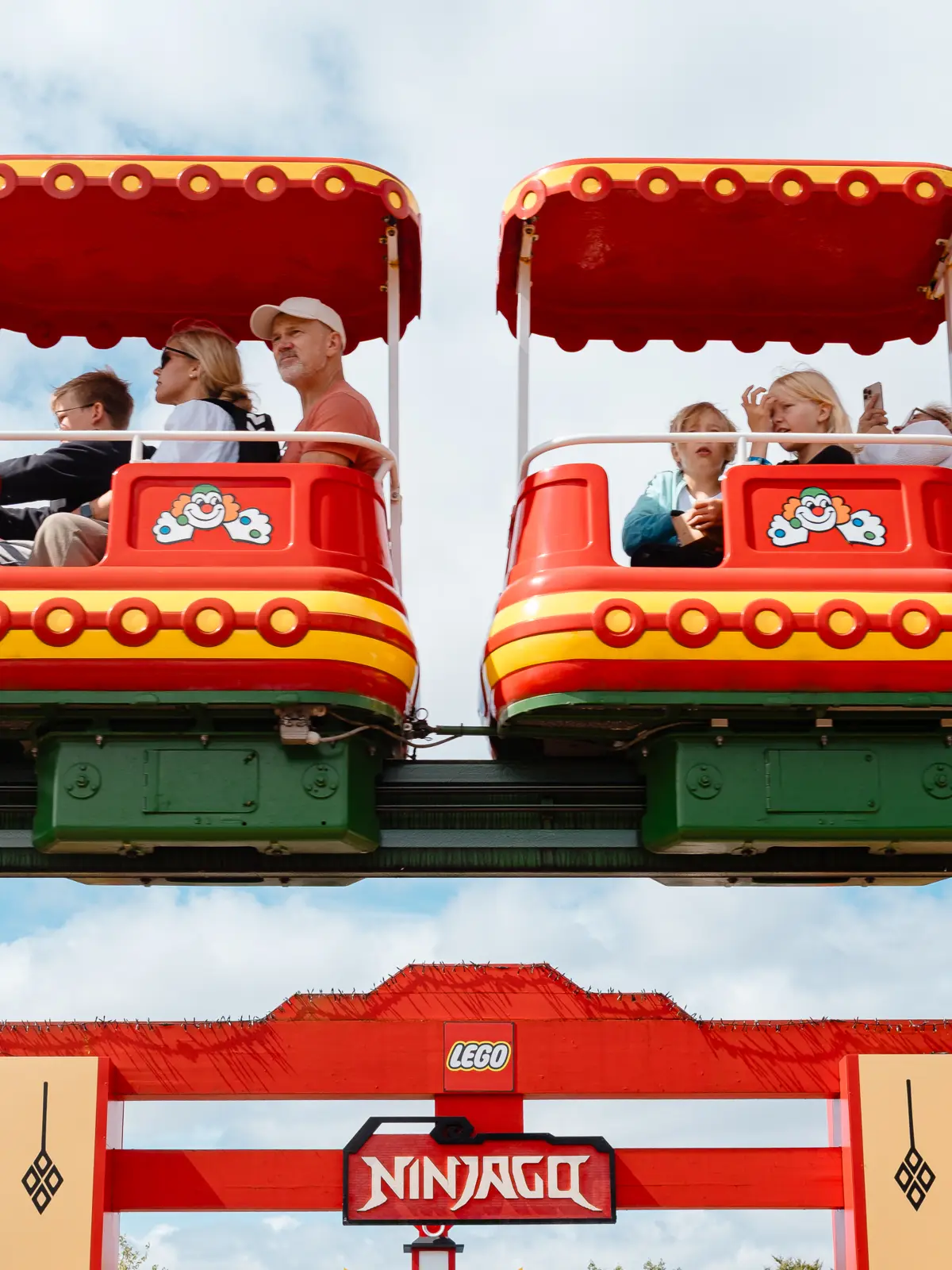 Legoland train cars with children and a dad who looks like he would rather be somewhere else.