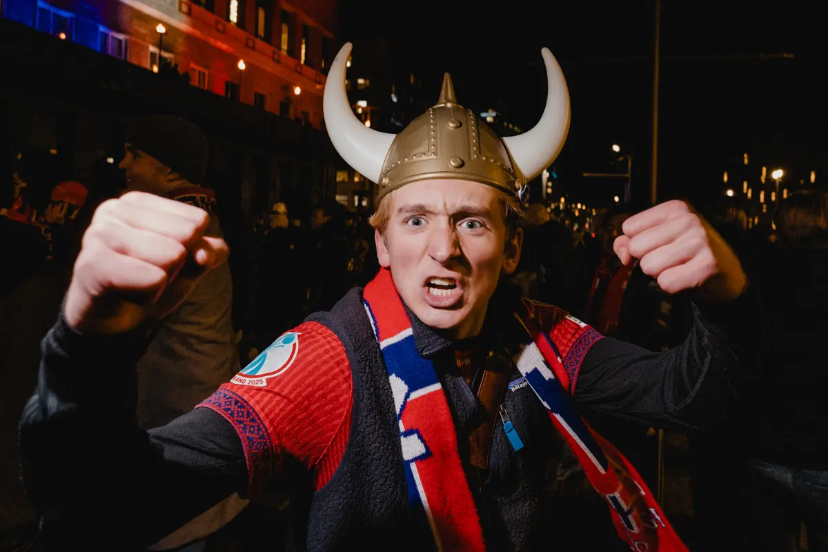 Young man in plastic viking helmet and Norwegian national soccer scarf making fists at the camera in celebration of Norway qualifying for the 2026 football world cup.