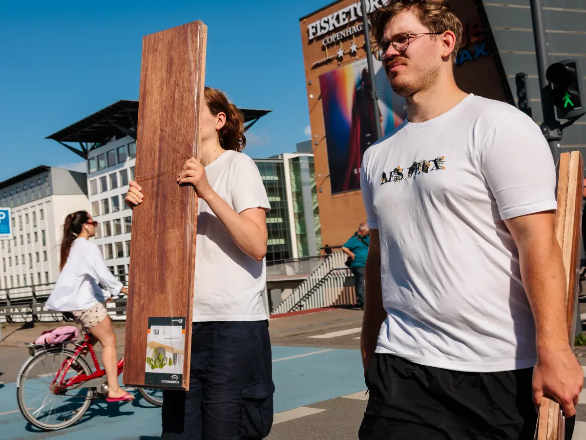 Woman on the street carrying a wooden board and seemingly smelling it.