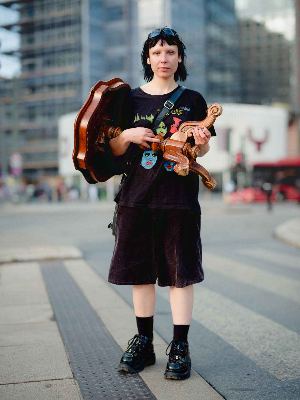Young woman dressed in black photographed on the street in Oslo while carrying a baroque side table