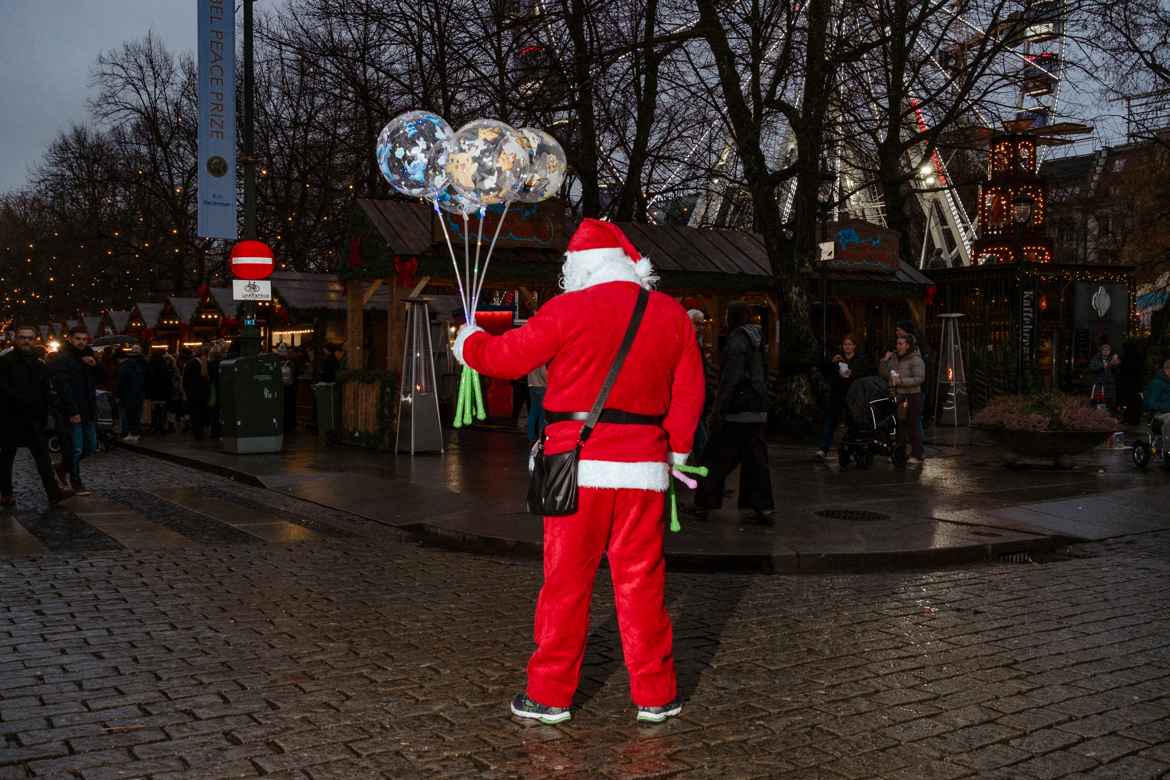 LED-filled balloon salesman in cheap santa costume on the wet Norvemner streets of Oslo.