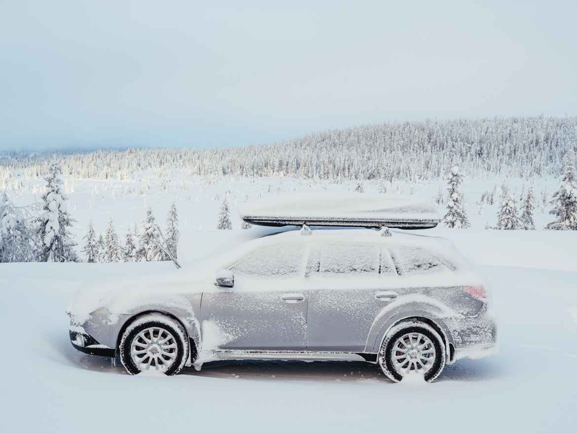 Station wagon with roof mounted ski box. Light show coating in a very white landscape.