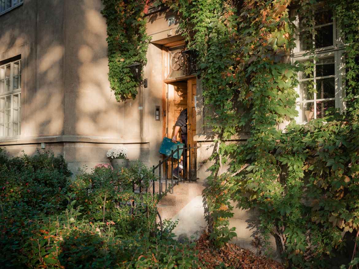 Electrician entering a doorway in a wall overgrown with woodbine at St Hanshaugen Oslo.