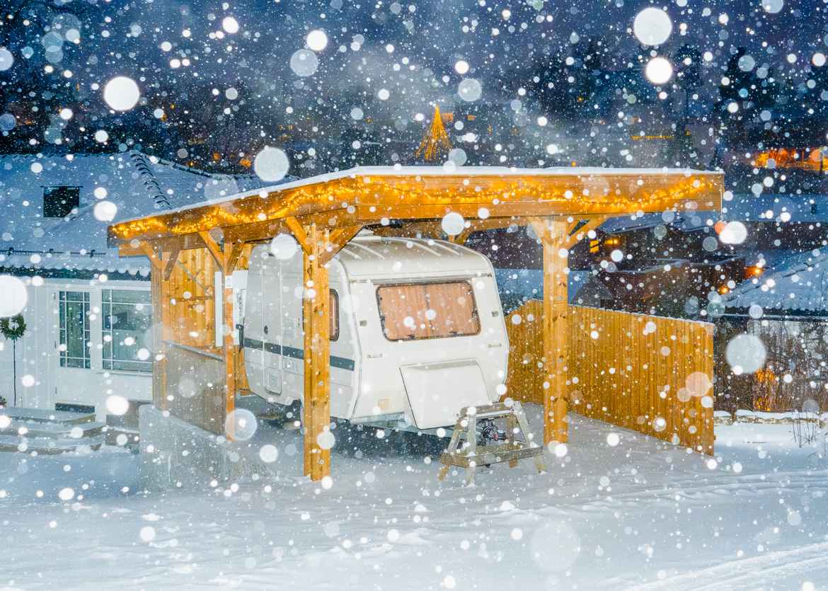 Caravan parked in car port while snow is falling.