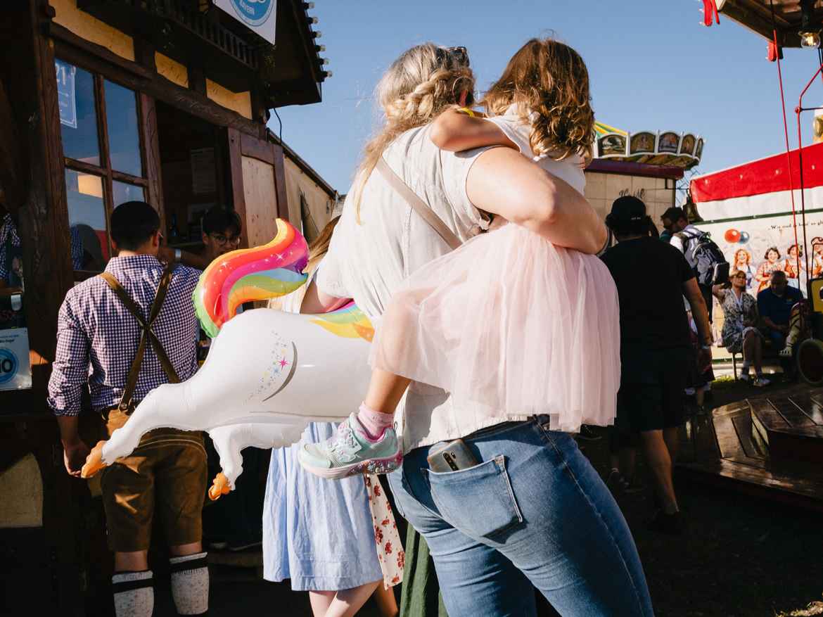 Woman carrying her daughter on the right arm and an inflated unicorn under her left.