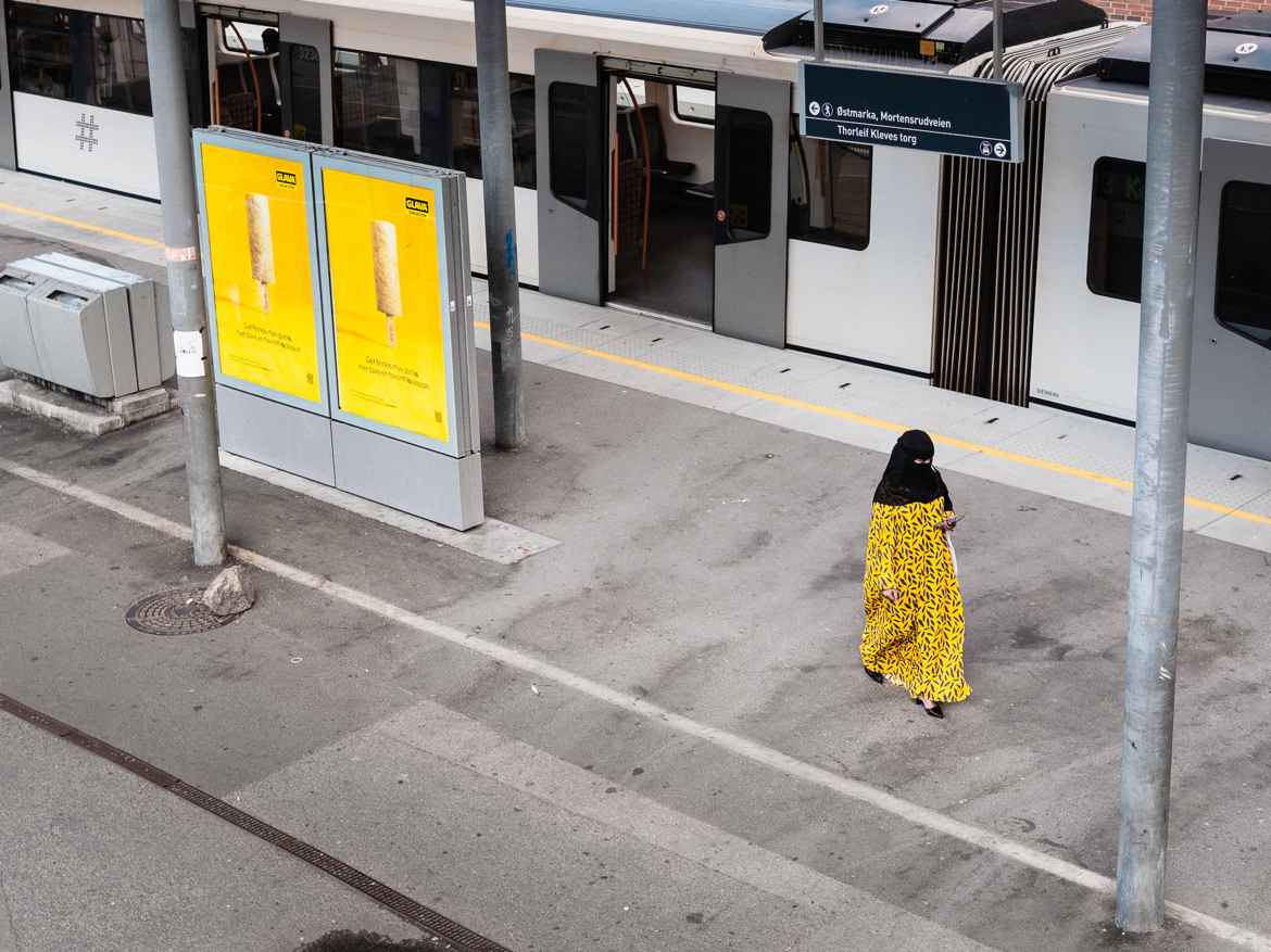 Woman in yellow burka juxtaposed medtro ad shells displaying yellow ads for Glava building insulation.